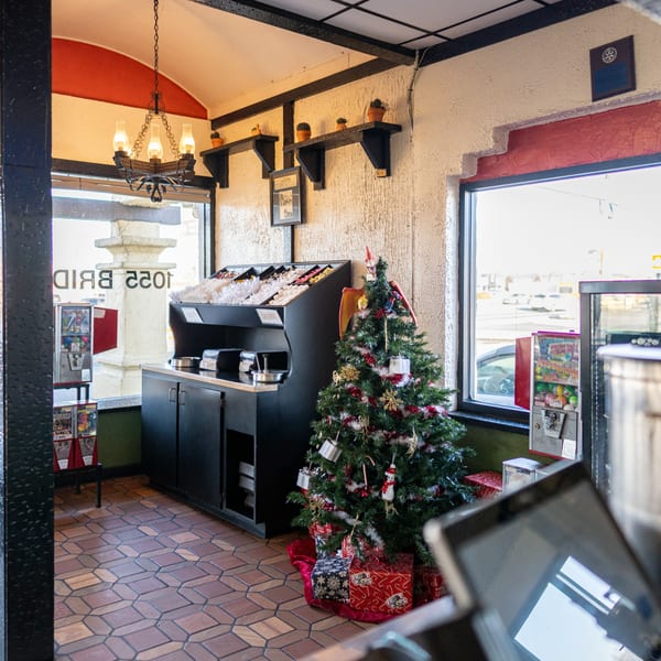 A festive Casa del Taco interior with a decorated Christmas tree, condiment bar, and tiled floor.