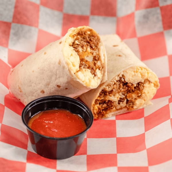 Two halves of a Casa del Taco burrito filled with meat and cheese, with a side of salsa.